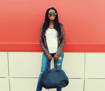 Fashionable happy young African woman with handbag in casual, stylish black girl posing in the city