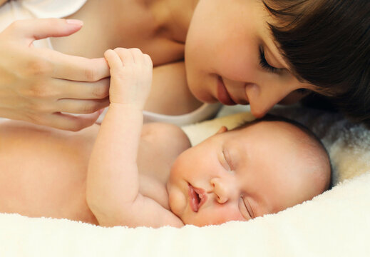 Happy mother and infant sweet sleeping lying on white bed