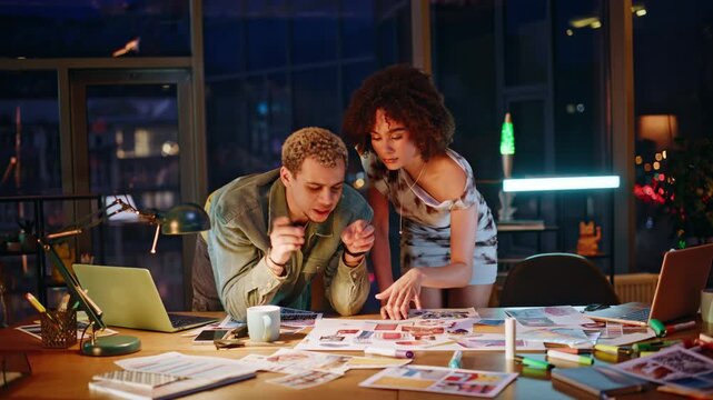 Designers reviewing mood board late night studio. Creatives brainstorming ideas