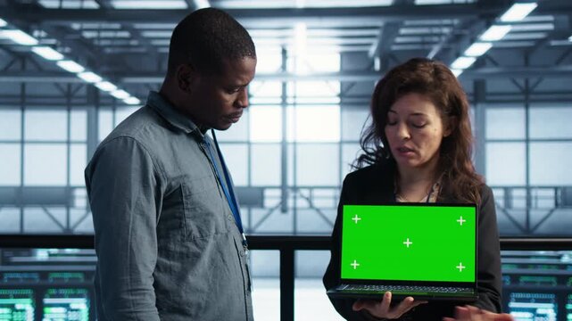 IT colleagues work in a server room with laptop as power settings, equipment maintenance and chroma key shape the infrastructure task within a controlled technical environment.