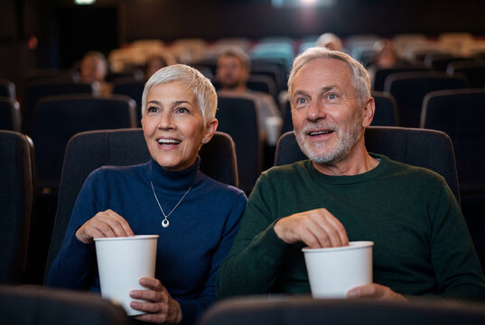 Senior couple eating popcorn while watching a movie
