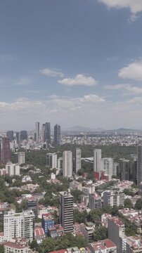 Aerial panoramic view flying forward over Polanco with skyline of Paseo de la Reforma and Bosque de Chapultepec, vertical video, shot in D-Log M