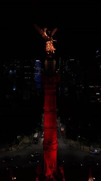 Vertical reveal of illuminated Angel of Independence rising to unveil Mexico City skyline at night