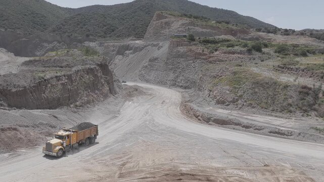 Heavy-Duty Mining Truck Hauling Load Through Dusty Open-Pit Quarry, Shot in D-Log M