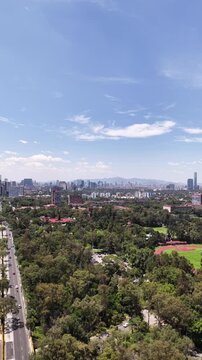 Drone Panning Across Ciudad Universitaria, UNAM, Sports Fields Toward Distant Mexico City Skyline, Vertical Video