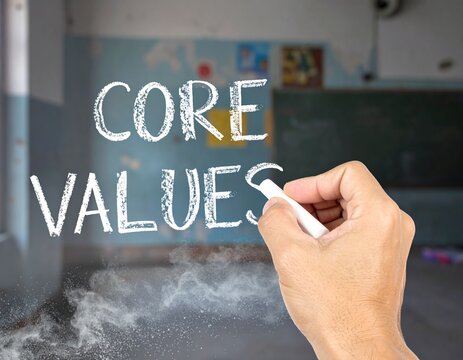 A hand draws the words core values on a blackboard, demonstrating the importance of ethical principles in business and personal life today and beyond.
