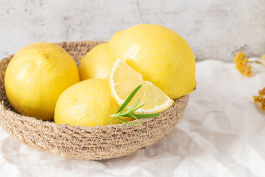 Fresh yellow lemons with rosemary sprigs in basket
