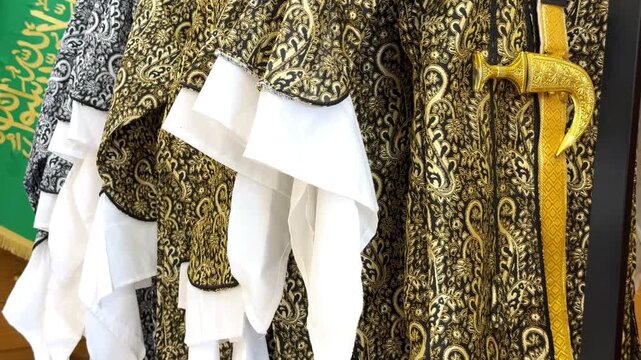 Traditional Saudi embroidered Bisht clothing with ceremonial golden dagger (Jambiya) hanging on display