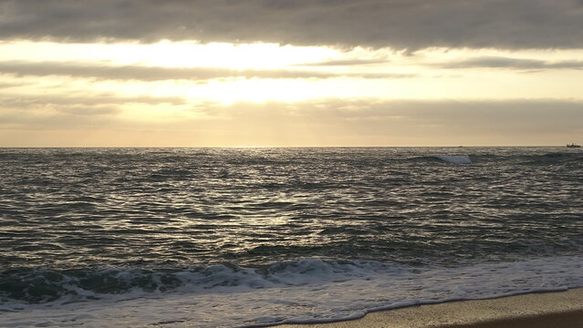 Bright morning sun breaking through clouds over rippling ocean.
A vivid early morning scene capturing golden sunlight streaming through cloudy skies and sparkling on the gentle waves of the sea.