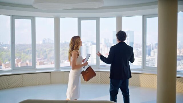 Real estate agent showing luxury apartment. Woman presenting flat city view.