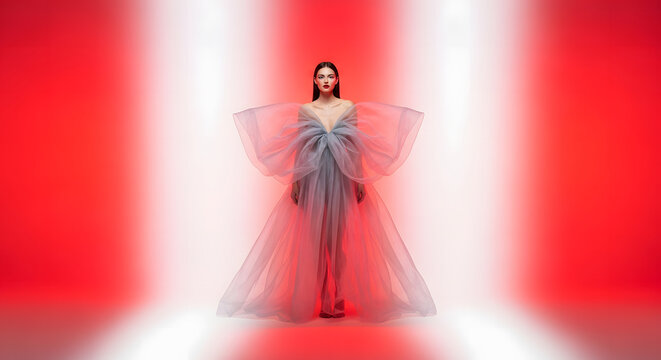 Elegant Woman in a Flowing Gown on a Red Stage with Spotlights.