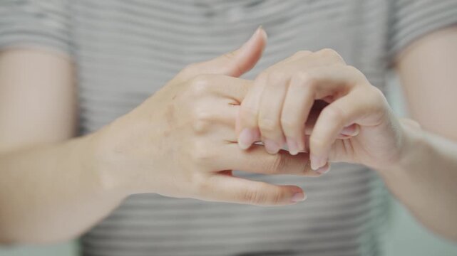 Close-up of a young woman massaging her painful finger joint, highlighting finger pain, joint stiffness, arthritis, hand discomfort, rehabilitation, healthcare, pain relief and physical therapy.
