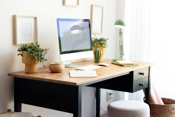 Plakat Stylish table with computer, houseplants and lamp near white wall in home office. Interior design