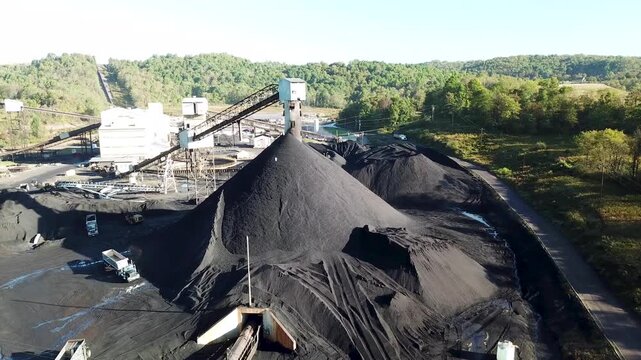 Aerial view of large coal mine processing plant with massive black fuel stockpiles and conveyor systems.