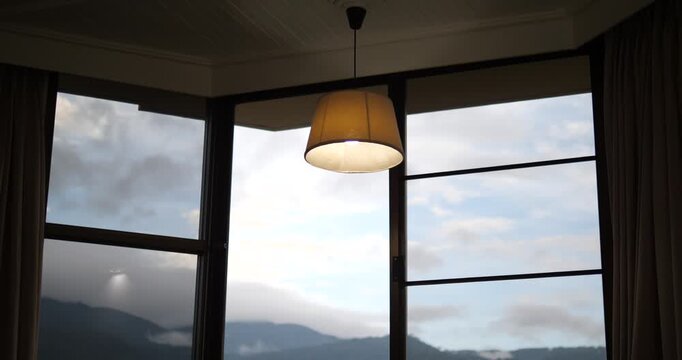 Mountain view through hotel room window with warm ceiling lamp
