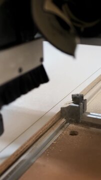CNC router cutting bit aligned over routed seam on laminated particleboard with guide rail, adjustable clamp, metal fixture, workshop surface, precision woodworking detail