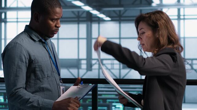 IT colleagues use documents in a server room to review technical documentation and system reports, combining documentation review, document review and maintenance reports.