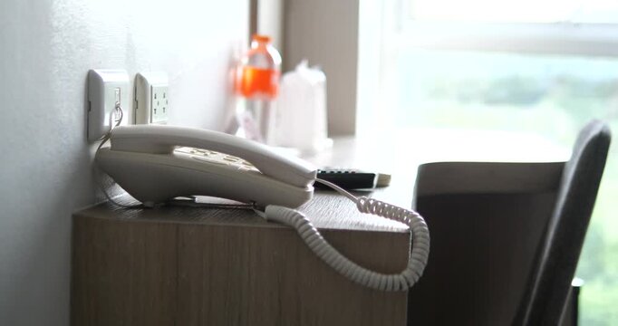 White landline telephone on wooden desk in hotel room