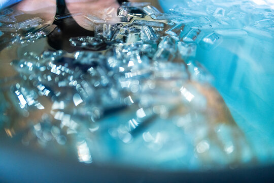 Close-up of an ice bath recovery session featuring a young man immersed in cold water and ice cubes. Perfect for wellness, athletic recovery, biohacking, mental resilience, and healthy lifestyle theme