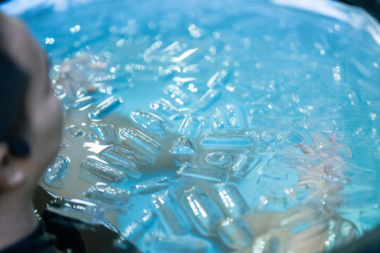 Young adult practicing cold water immersion surrounded by floating ice cubes after exercise. Suitable for sports recovery, muscle regeneration, physical endurance, wellness therapy, and healthy lifest