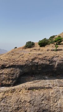 Vertical video aerial of Ratangad fort caves and cliff Maharashtra India