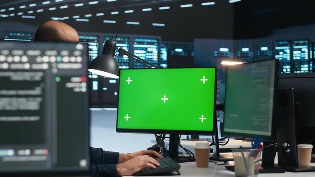 Technician runs code on a green screen computer in a server room while troubleshooting servers and using a mockup monitor for screen replacement in an editable server room workflow.
