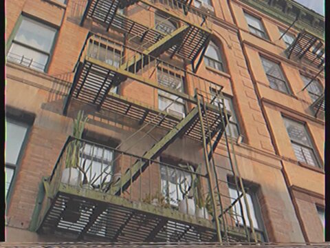 Low-angle view of a vintage new york city brownstone building with an iconic fire escape, showcasing urban architecture with a retro vhs effect and authentic film grain