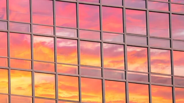 Vibrant sunset sky reflection on the modern glass windows of a skyscraper facade