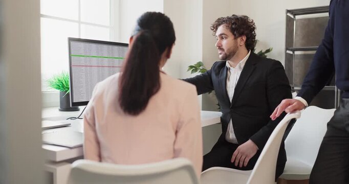 Manager briefs team on data in office. He explains charts on the monitor, linking audit results to strategy and planning for finance goals. Modern office scene supports effective teamwork.