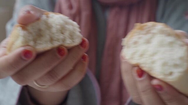Close up shot of woman hands breaking fresh baked dinner roll bread showing soft texture inside