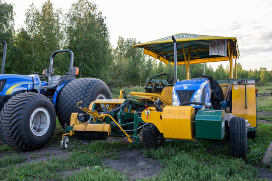 TYUMEN, RUSSIA - AUGUST 15, 2013: blue tractor connected to sod harvesting equipment near tree line
