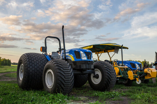 TYUMEN, RUSSIA - AUGUST 15, 2013: blue tractor with sod harvesting equipment stands under sunset sky