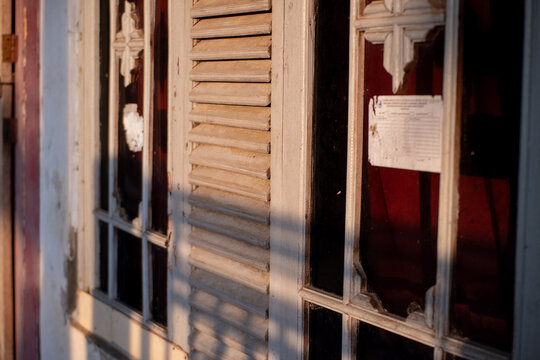 Old weathered wooden window with louvers illuminated by warm sunlight