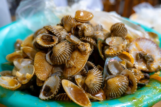 Pile of boiled clams in spicy sauce served in a green bowl