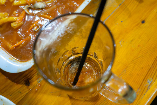 Empty glass of iced tea with a black straw on a wooden table