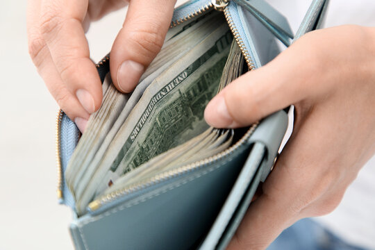 Persons hands holding a light blue wallet full of united states hundred dollar bills financial management and wealth