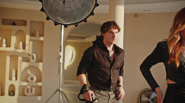 Man taking photos redhead model studio. Photographer crouching directing fashion