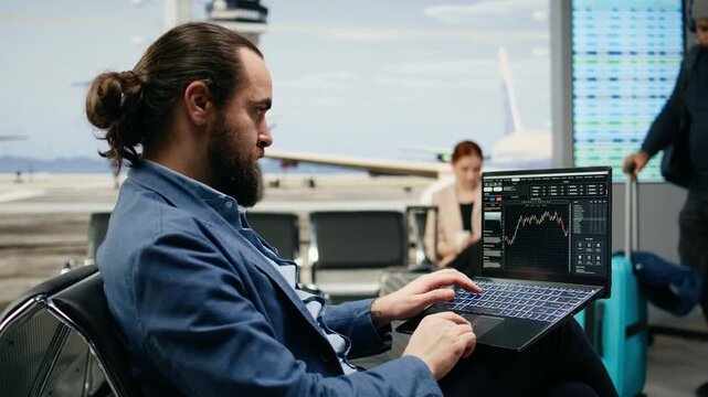 Businessman monitors trading data and stock exchange graphs on a laptop near an airport gate while tracking financial forecasts and investments.