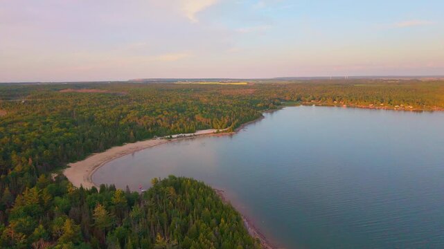 Bruce Penisula, Canada - July 8 2026: A stunning 4K aerial drone view of Singing Sands Beach in the Bruce Peninsula, showcasing shallow turquoise waters, soft sandy shores, and lush coastal forests.