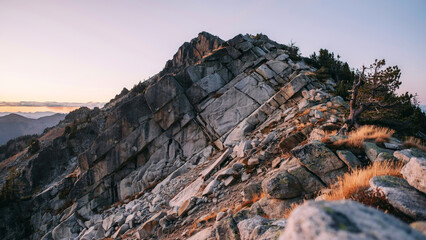 Obraz premium Rocky mountain peak at sunrise. Jagged cliff summit during golden hour light.