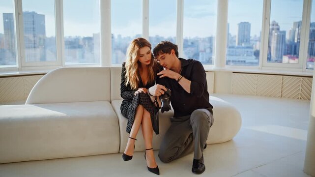 Photographer showing model camera images loft studio. Fashion shoot teamwork.