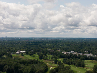 Fototapeta premium Aerial drone view of distant city skyline beyond a wooded suburban landscape in Bayberry Park, New Rochelle, New York
