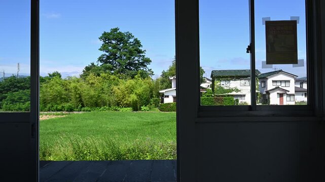 駅舎の扉から眺める夏の緑豊かな田園風景