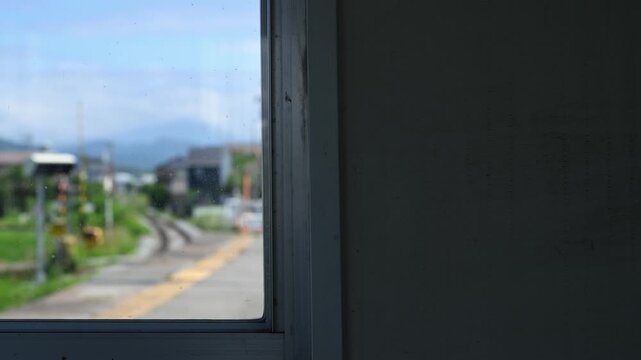 窓枠越しに眺める線路と踏切のある長閑な風景