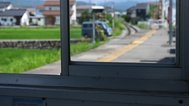 窓枠越しに眺める線路と踏切のある長閑な風景