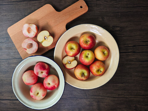 Red apple pink peach fruit whole sliced half seed tin plate chopping board wooded background