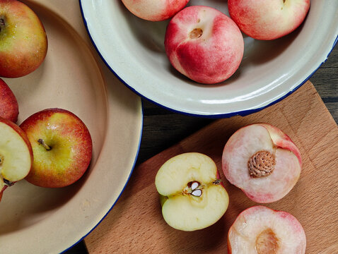 Red apple pink peach fruit whole sliced half seed tin plate chopping board wooded background