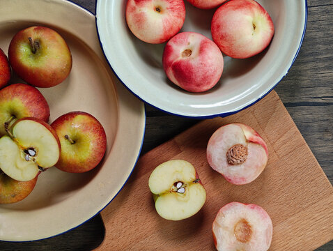 Red apple pink peach fruit whole sliced half seed tin plate chopping board wooded background