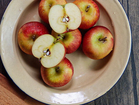 Red apple pink peach fruit whole sliced half seed tin plate chopping board wooded background