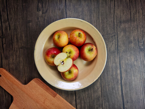 Red apple pink peach fruit whole sliced half seed tin plate chopping board wooded background
